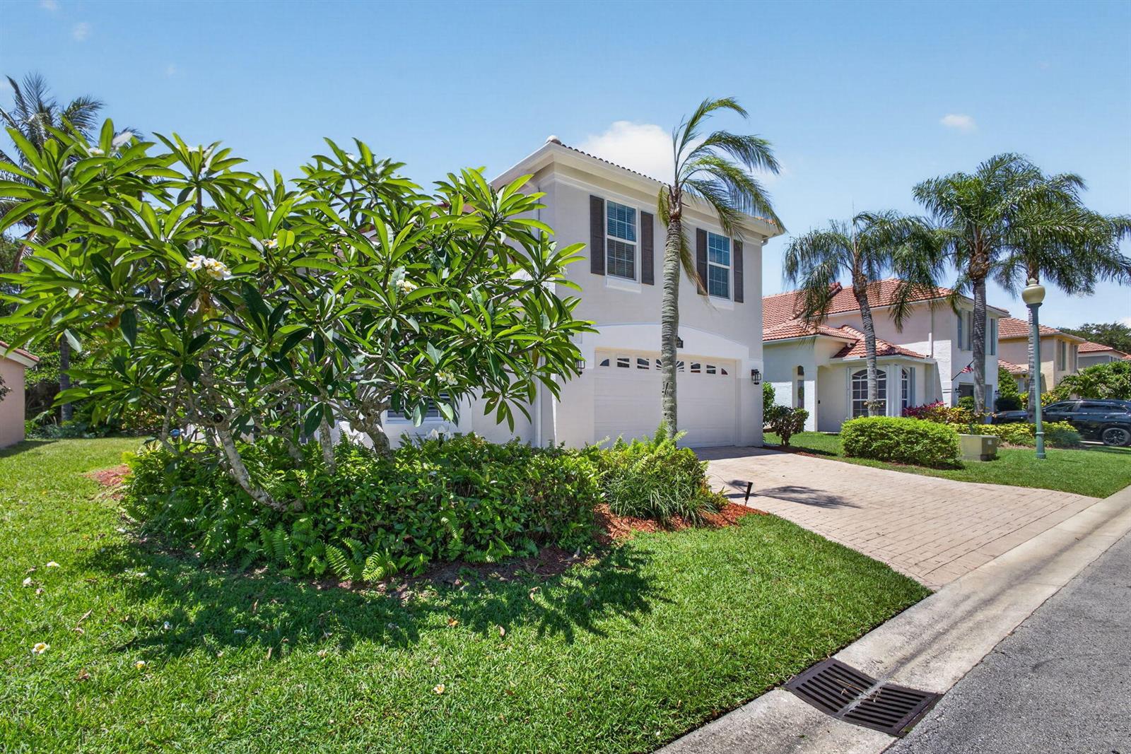 A two-story suburban house with a paved driveway, a garage, and lush landscaping — 5137 Elpine Way, Riviera Beach FL 33418, RIVIERA BEACH, FL