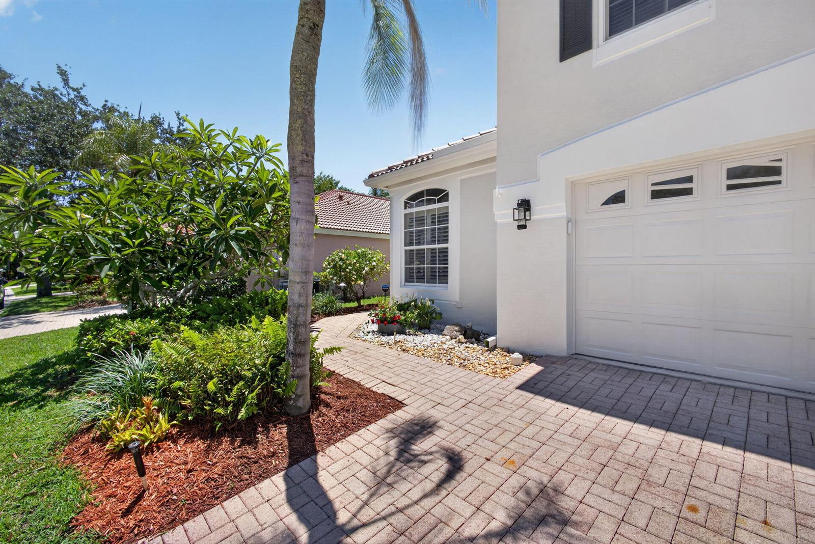 A paved walkway leads to the side of a house with a white garage door — 5137 Elpine Way, Riviera Beach FL 33418, RIVIERA BEACH, FL
