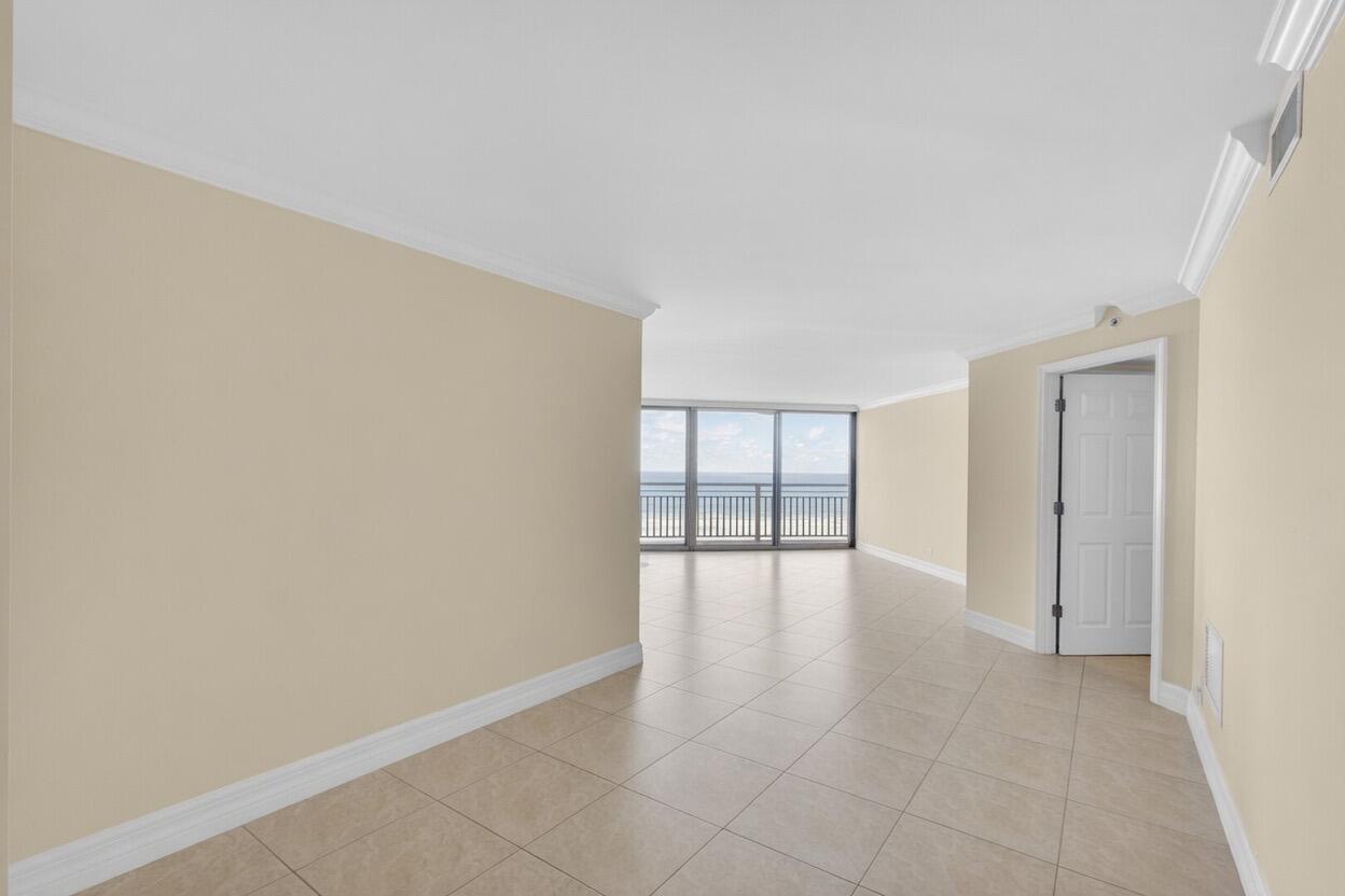 An empty room with beige walls, tile flooring, and a sliding glass door overlooking the ocean — 3000 N Ocean Drive # B, Singer Island FL 33404, SINGER ISLAND, FL