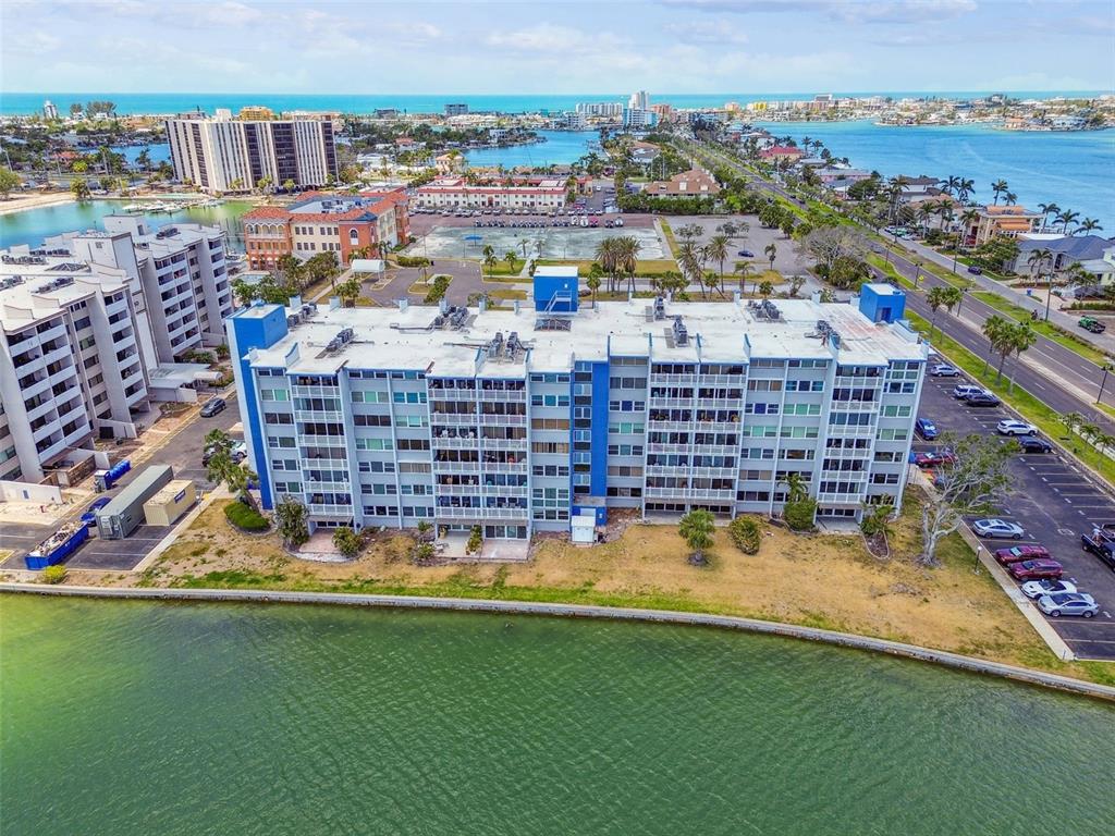 An aerial view of a multi-story apartment building situated along a waterfront with parking lots — 500 TREASURE ISLAND CAUSEWAY UNIT 607, ST PETERSBURG, FL