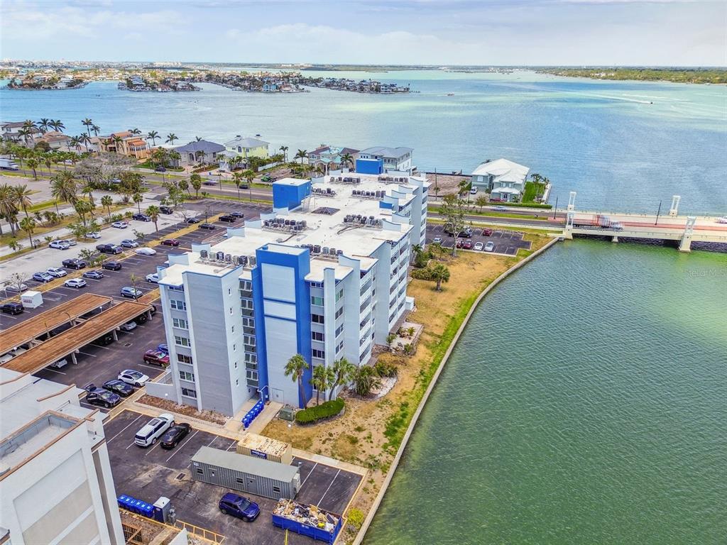 An aerial view shows a multi-story apartment building situated next to a bridge and water — 500 TREASURE ISLAND CAUSEWAY UNIT 607, ST PETERSBURG, FL