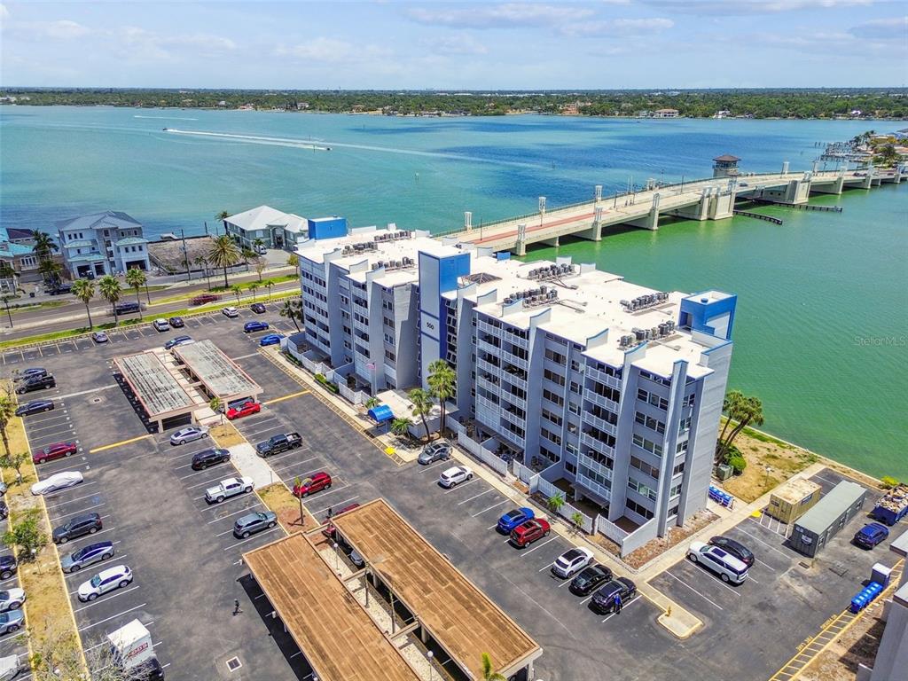 An aerial view shows a multi-story apartment building with a parking lot next to a bridge — 500 TREASURE ISLAND CAUSEWAY UNIT 607, ST PETERSBURG, FL