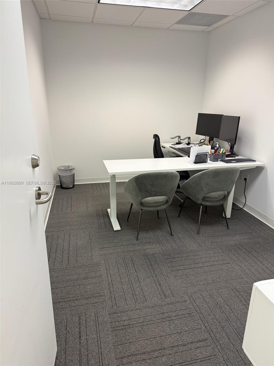 A small office features a white desk, two gray chairs, and gray carpeted flooring — 1101 Brickell Ave, FL 33131, FL