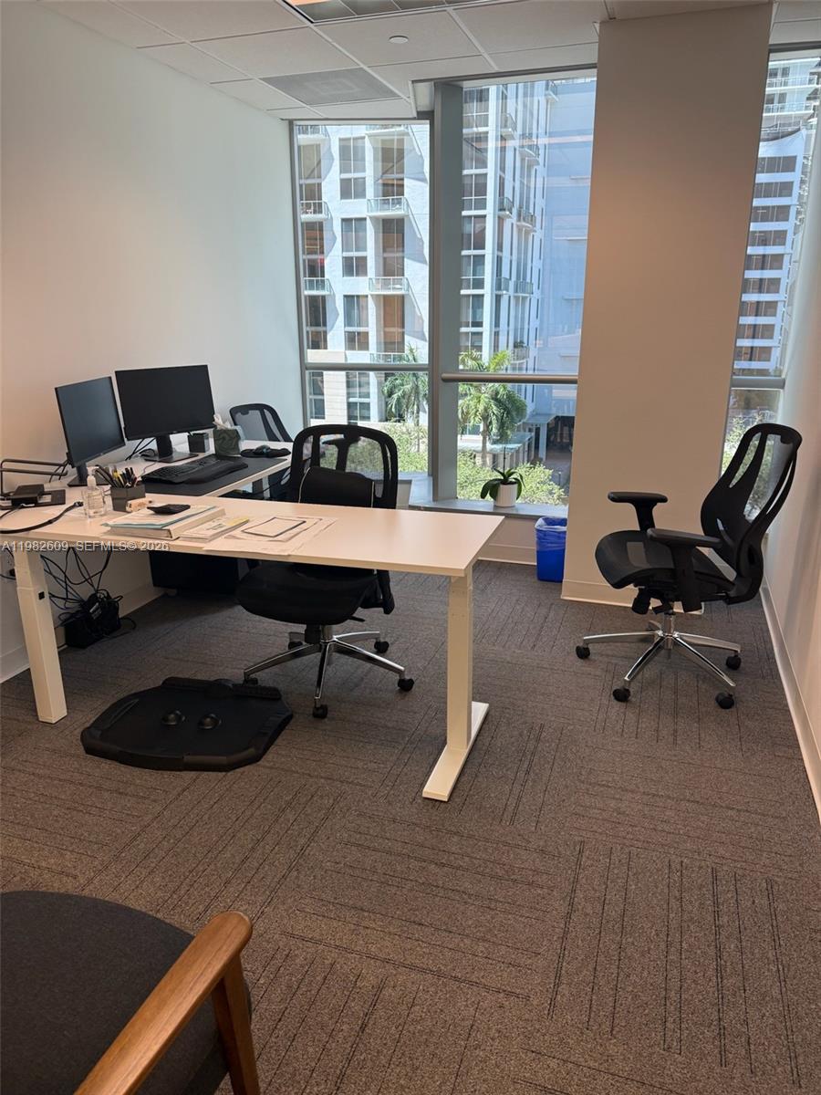An office space features a white desk, two black chairs, and floor-to-ceiling windows — 1101 Brickell Ave, FL 33131, FL