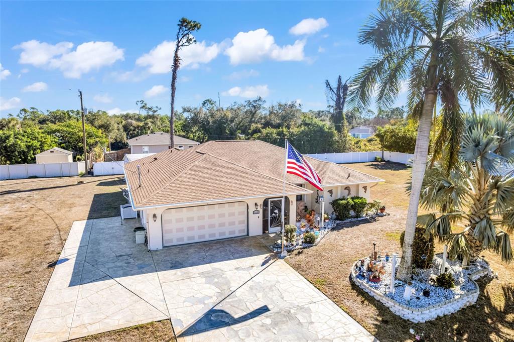 An aerial view of a single-story house with a flag, palm tree, and paved driveway — 2298 CEDARWOOD STREET, PORT CHARLOTTE, FL