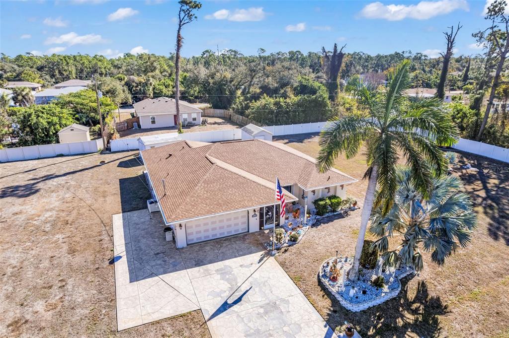 An aerial view shows a single-story house with a tan roof, garage, and palm trees — 2298 CEDARWOOD STREET, PORT CHARLOTTE, FL
