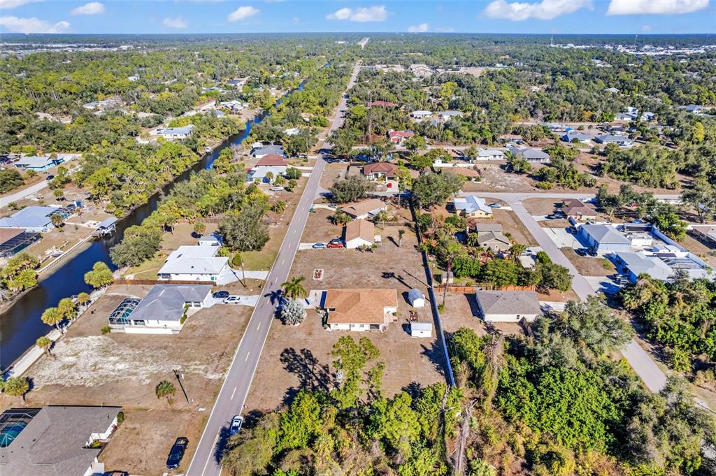 An aerial view shows a residential neighborhood with houses, a canal, and a paved road — 2298 CEDARWOOD STREET, PORT CHARLOTTE, FL