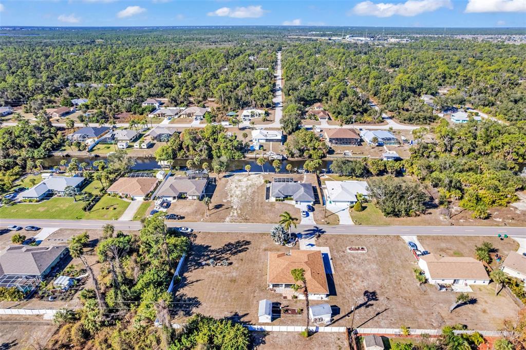 An aerial view shows a residential neighborhood with houses, a canal, and vacant lots — 2298 CEDARWOOD STREET, PORT CHARLOTTE, FL