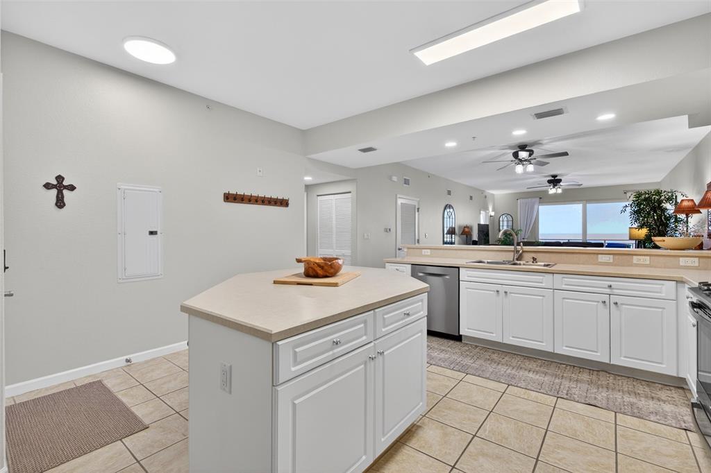A kitchen features white cabinets, a central island, and tile flooring, opening to a living area — 80 SURFVIEW DRIVE UNIT 811, PALM COAST, FL