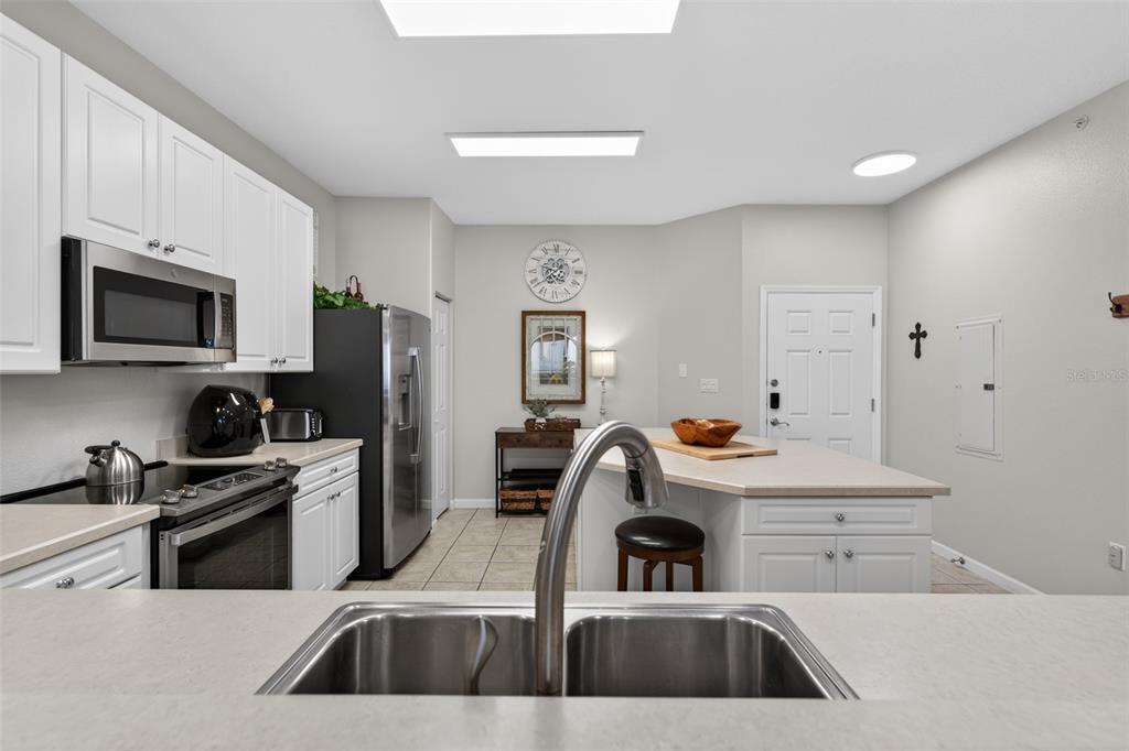 A kitchen features white cabinets, stainless steel appliances, a center island, and tile flooring — 80 SURFVIEW DRIVE UNIT 811, PALM COAST, FL