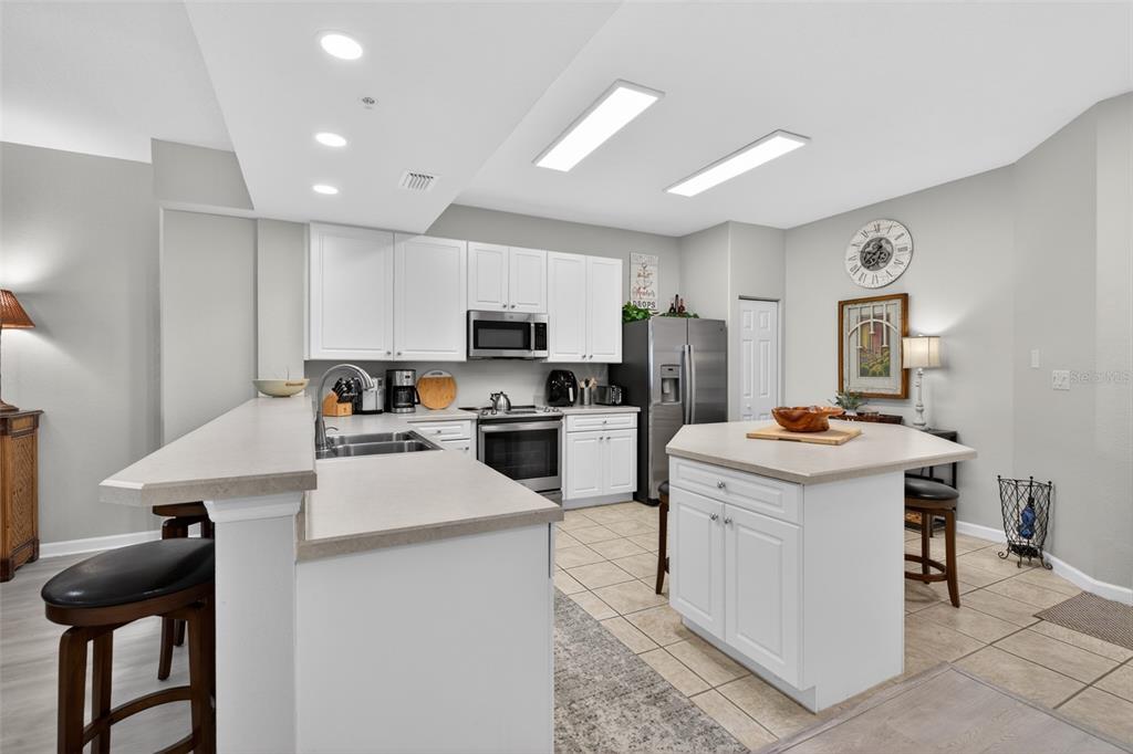 A kitchen features white cabinets, stainless steel appliances, a center island, and tile flooring — 80 SURFVIEW DRIVE UNIT 811, PALM COAST, FL