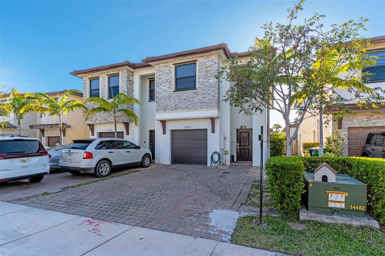 A two-story residential building features a stone facade, a paved driveway, and a brown garage — 24900 SW 107th Ct, Homestead FL 33032, HOMESTEAD, FL