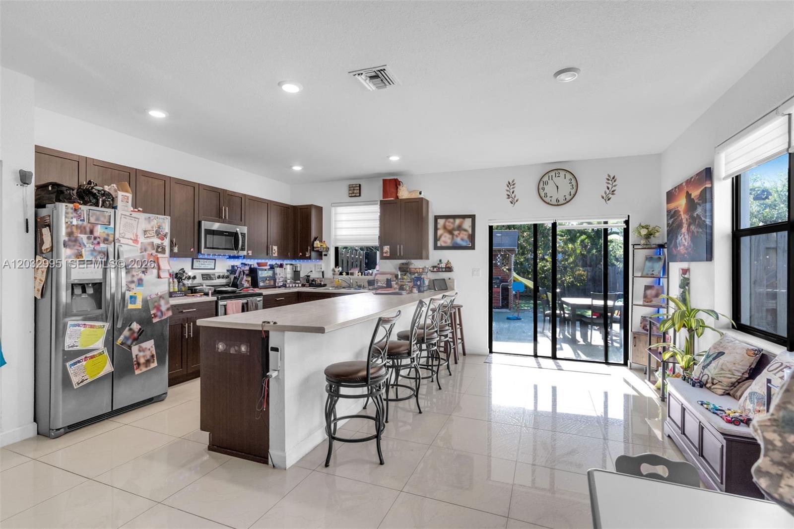 A kitchen with dark wood cabinets, a breakfast bar, and sliding glass doors to a patio — 24900 SW 107th Ct, Homestead FL 33032, HOMESTEAD, FL