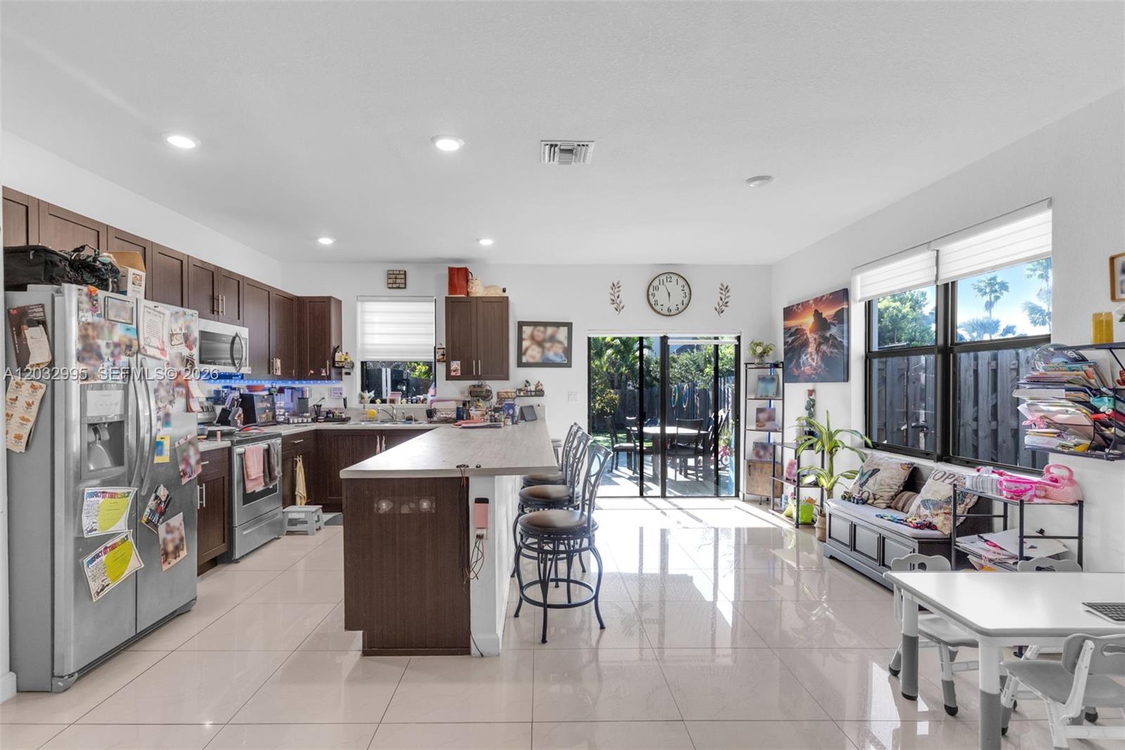 A kitchen with dark wood cabinets, a large island with bar seating, and tile flooring — 24900 SW 107th Ct, Homestead FL 33032, HOMESTEAD, FL