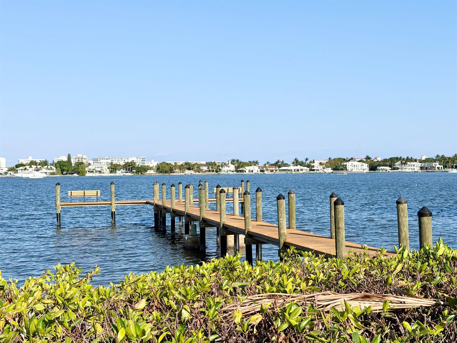 A wooden pier with a bench extends into a calm bay with distant coastal homes — 720 N Dixie Highway # 604, Lantana FL 33462, LANTANA, FL