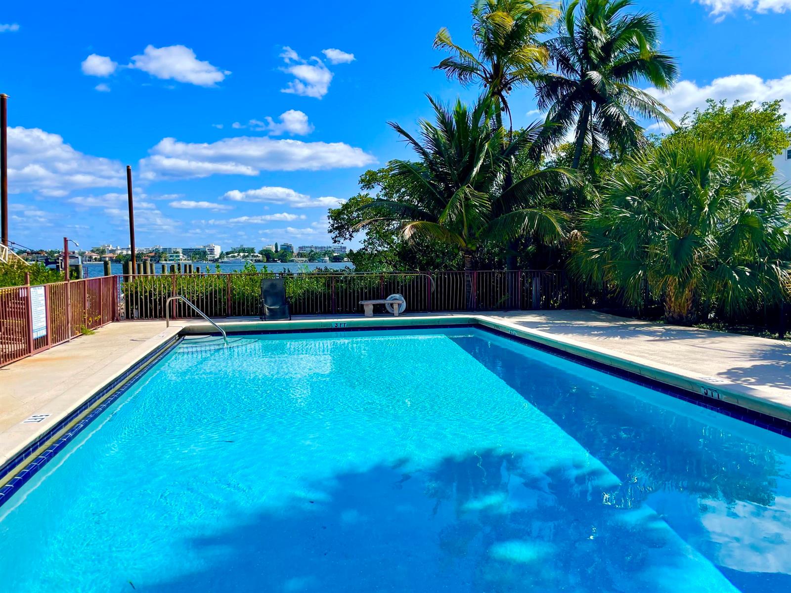 A swimming pool with a metal fence overlooks a waterway and palm trees — 720 N Dixie Highway # 604, Lantana FL 33462, LANTANA, FL
