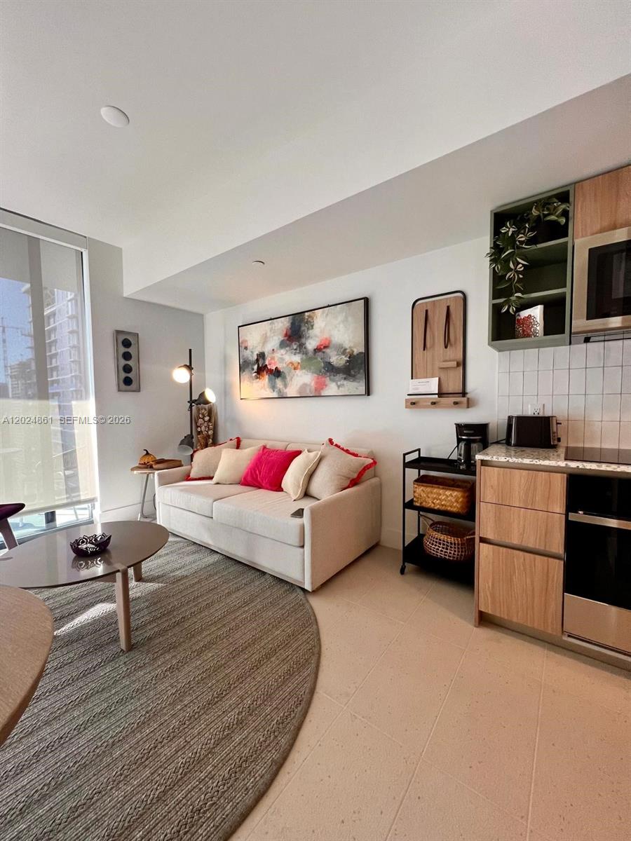 A modern living room features a beige sofa, a circular rug, and an adjacent kitchenette — 159 NE 6th St # 2508, Miami FL 33132, MIAMI, FL