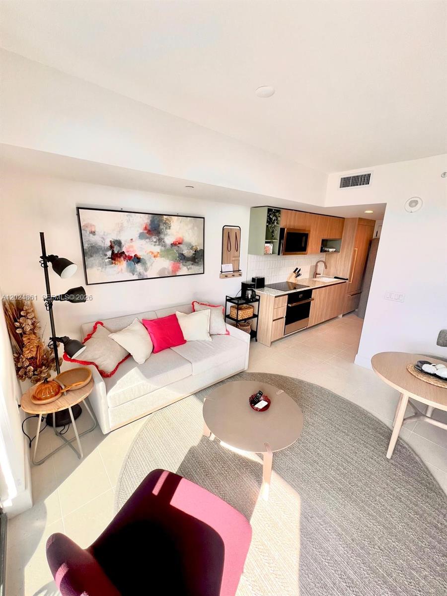A modern studio apartment features a kitchenette, a sofa with colorful pillows, and a rug — 159 NE 6th St # 2508, Miami FL 33132, MIAMI, FL