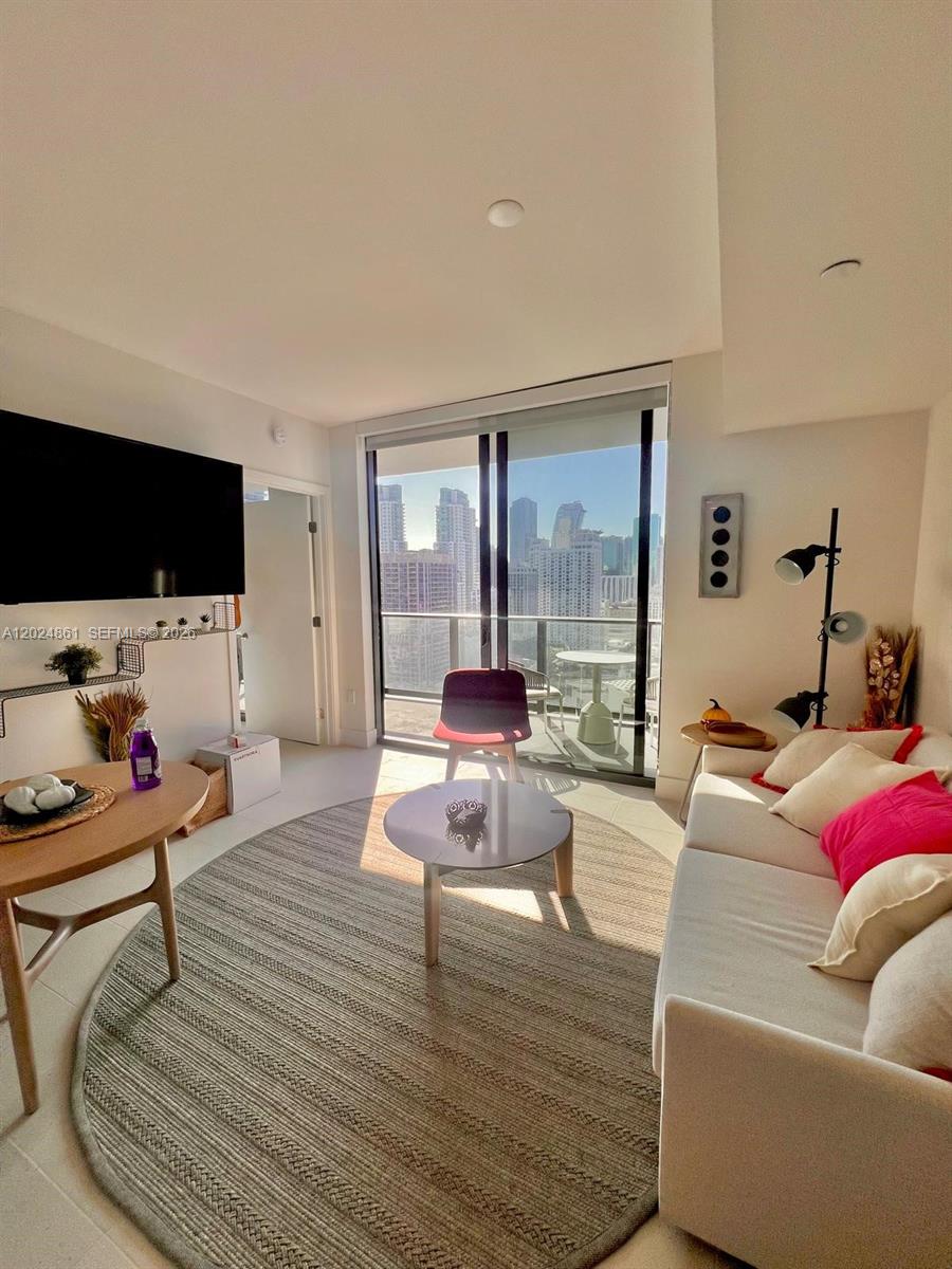 A modern living room features a white sofa, a circular rug, and floor-to-ceiling windows — 159 NE 6th St # 2508, Miami FL 33132, MIAMI, FL