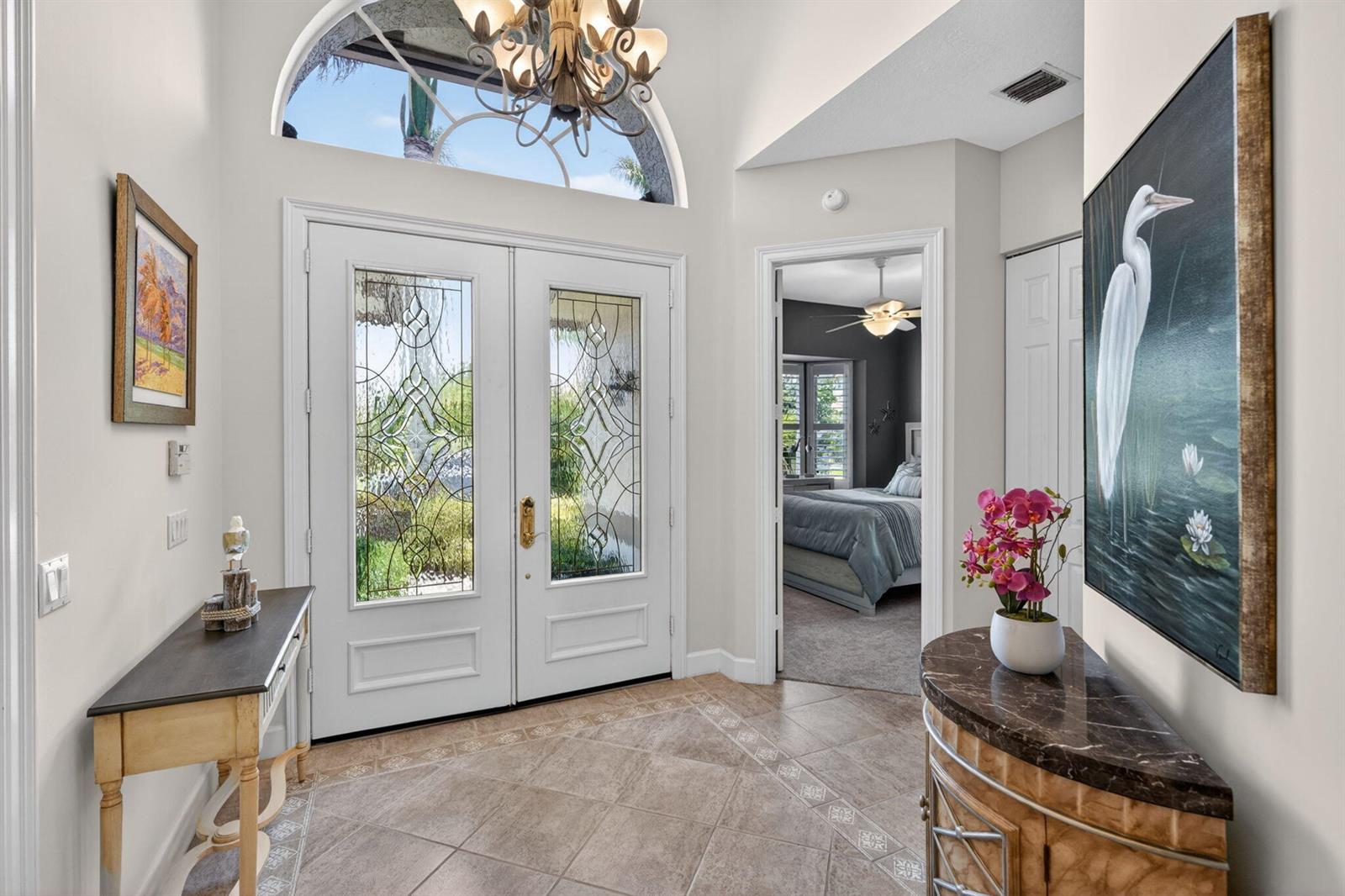 A bright foyer features double glass-paneled doors, tile flooring, and a view into a bedroom — 7982 SE Hempstead Circle, Hobe Sound FL 33455, HOBE SOUND, FL