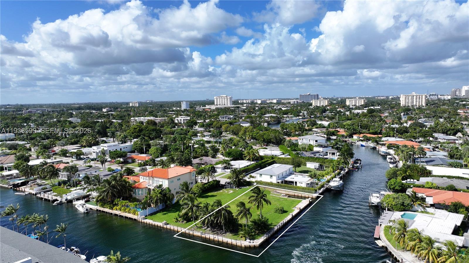 An aerial view shows a vacant waterfront lot bordered by a canal and residential homes — 2210 NE 124th St, North Miami FL 33181, NORTH MIAMI, FL