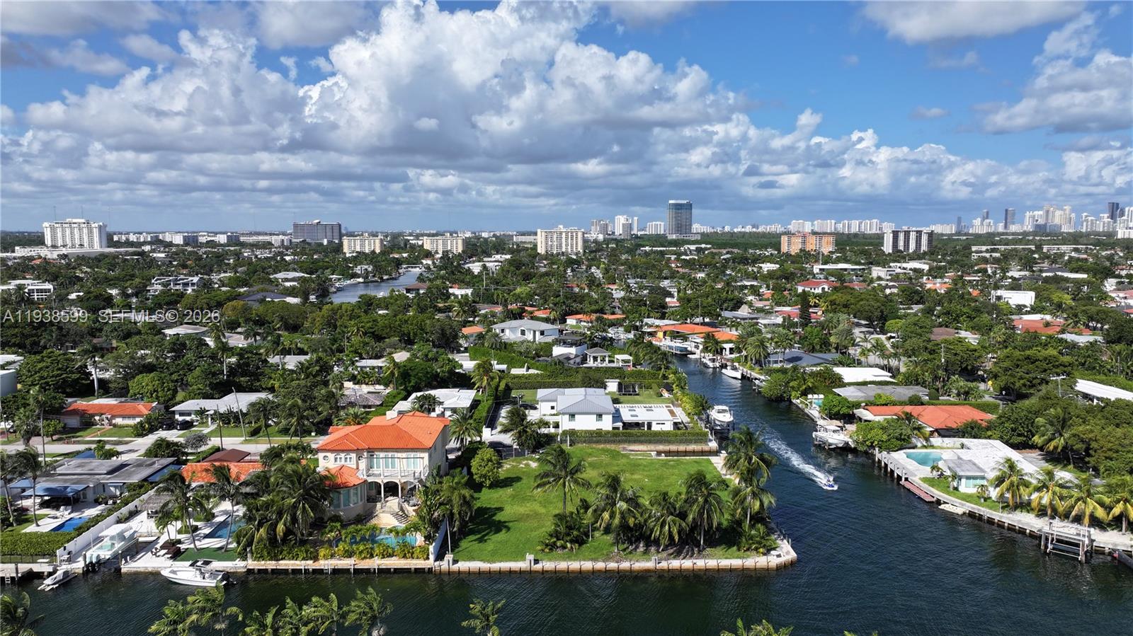 An aerial view shows a waterfront house with a red roof beside a canal — 2210 NE 124th St, North Miami FL 33181, NORTH MIAMI, FL
