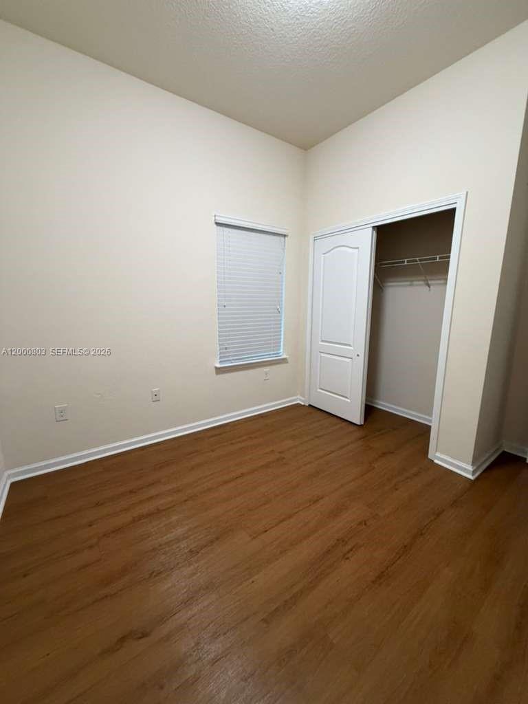 An empty bedroom features light-colored walls, wood-look flooring, a window with blinds, and a closet — 2105 Golden Lake Loop St, St Augustine FL 32084, ST AUGUSTINE, FL