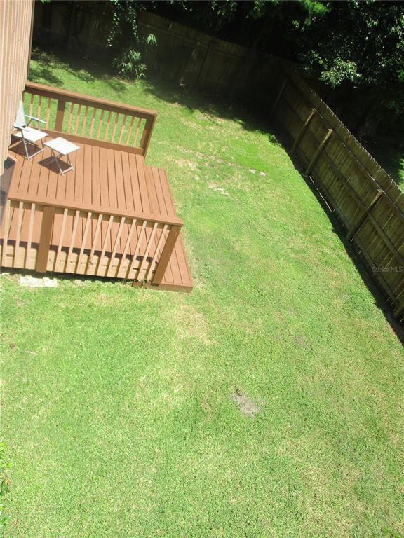 A wooden deck with a small table and chairs overlooks a grassy backyard with fencing — 1631 NW 94TH STREET, GAINESVILLE, FL