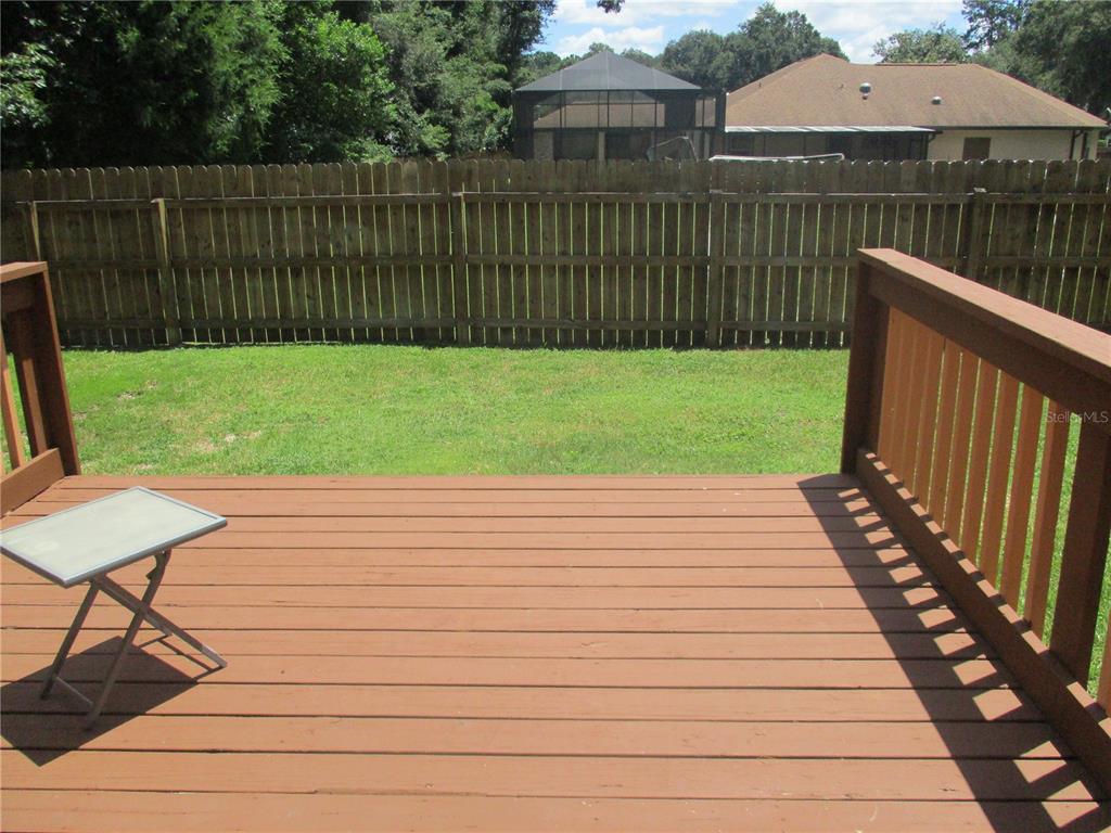 A wooden deck overlooks a grassy backyard enclosed by a wooden privacy fence — 1631 NW 94TH STREET, GAINESVILLE, FL