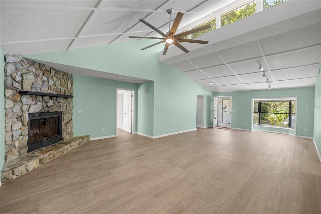 A spacious living room features light green walls, a stone fireplace, and wood-look flooring — 11599 W TIMBERLANE DRIVE, HOMOSASSA, FL