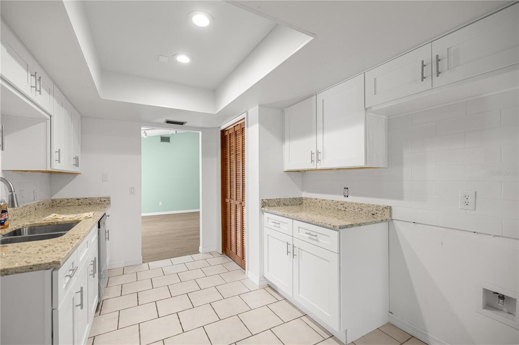 A kitchen features white cabinets, granite countertops, tile flooring, and a doorway leading to another room — 11599 W TIMBERLANE DRIVE, HOMOSASSA, FL