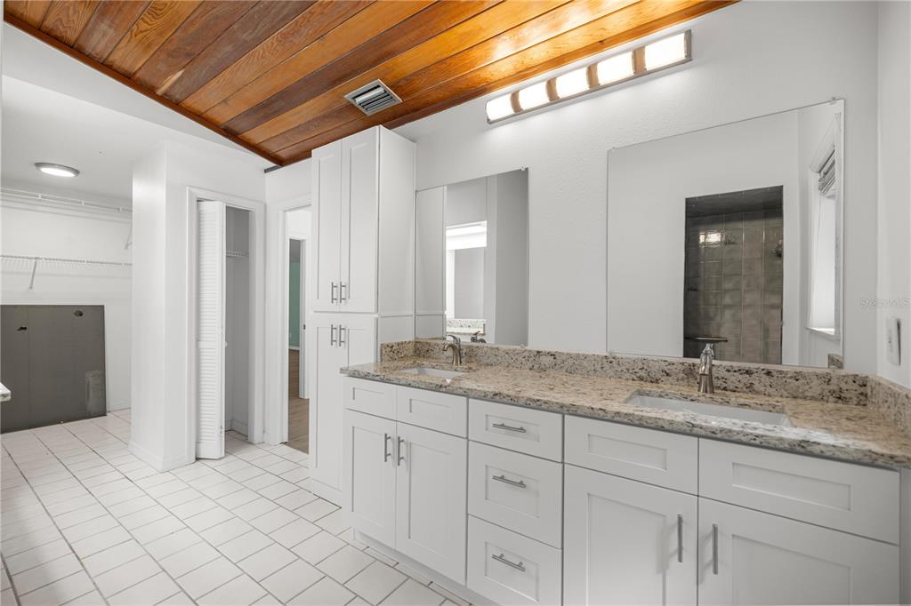 A bathroom features a double vanity with granite countertops, white cabinetry, and a wood-paneled ceiling — 11599 W TIMBERLANE DRIVE, HOMOSASSA, FL