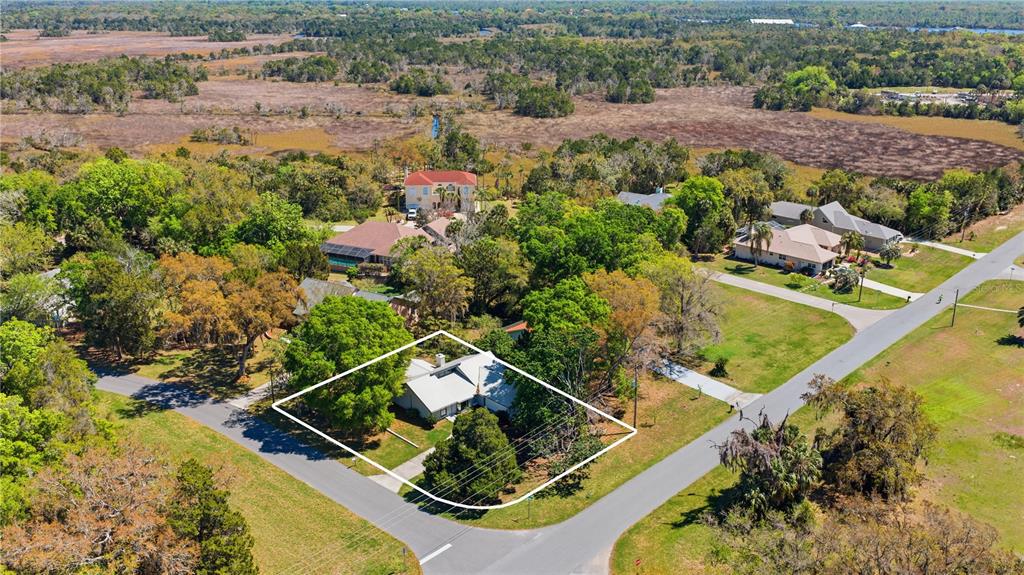 An aerial view shows a single-story house with a white roof surrounded by trees — 11599 W TIMBERLANE DRIVE, HOMOSASSA, FL