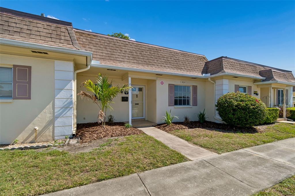 A single-story townhouse with a brown shingled roof, beige stucco walls, and a front walkway — 1614 S LAKE AVENUE UNIT 2, CLEARWATER, FL