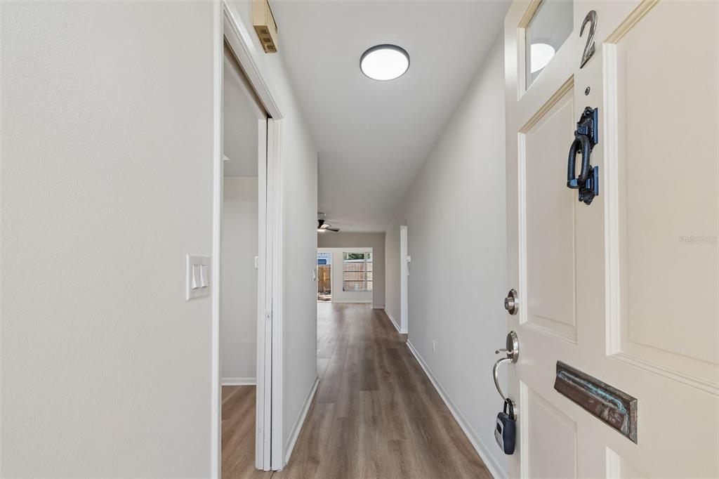 A view from an open front door looking down a hallway with light wood flooring — 1614 S LAKE AVENUE UNIT 2, CLEARWATER, FL