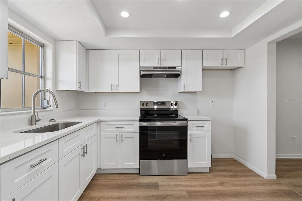 A kitchen with white cabinets, stainless steel appliances, and light wood-look flooring — 1614 S LAKE AVENUE UNIT 2, CLEARWATER, FL