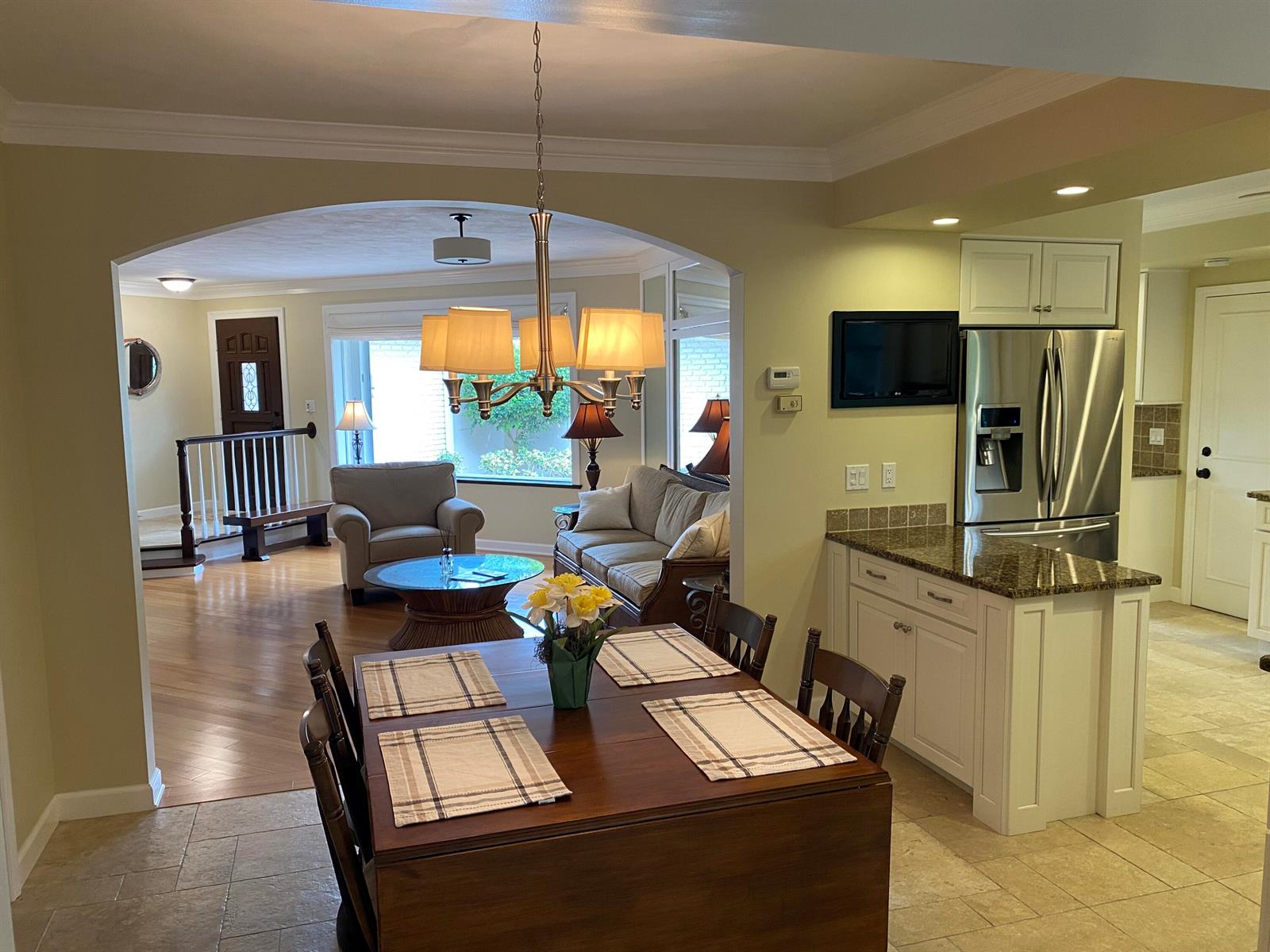 A dining area with a wooden table sits in front of an open living room — 535 Flamevine Lane, Vero Beach FL 32963, VERO BEACH, FL