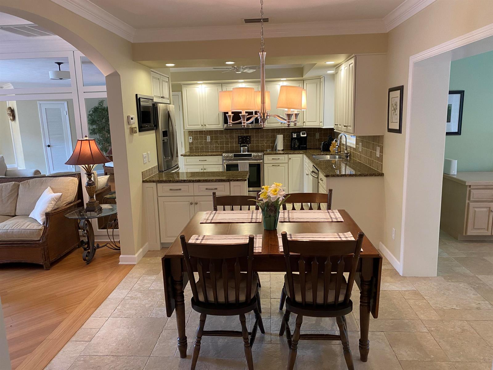 A dining area with a wooden table and chairs sits in front of a kitchen — 535 Flamevine Lane, Vero Beach FL 32963, VERO BEACH, FL
