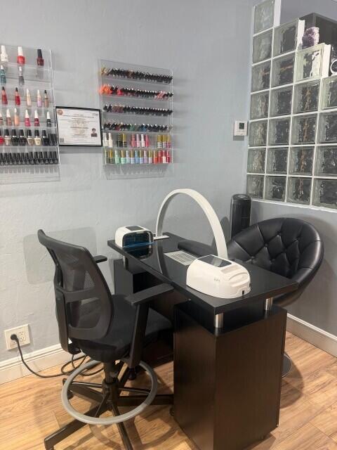 A nail salon station features a black desk, two chairs, and wall-mounted polish displays — 900 E Atlantic Boulevard, Pompano Beach FL 33060, POMPANO BEACH, FL