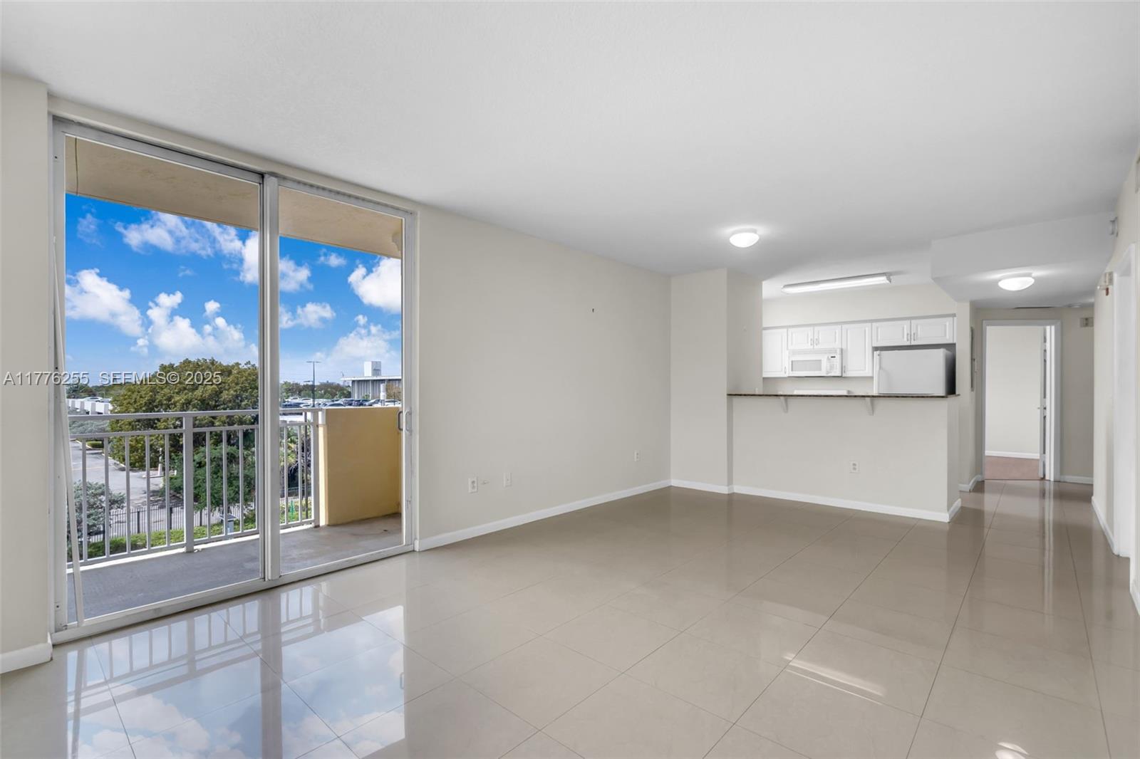 An open-concept living area features light-colored tile flooring, a kitchen with white cabinets, and a balcony — 215 SW 42nd Ave # 402, Miami FL 33134, MIAMI, FL