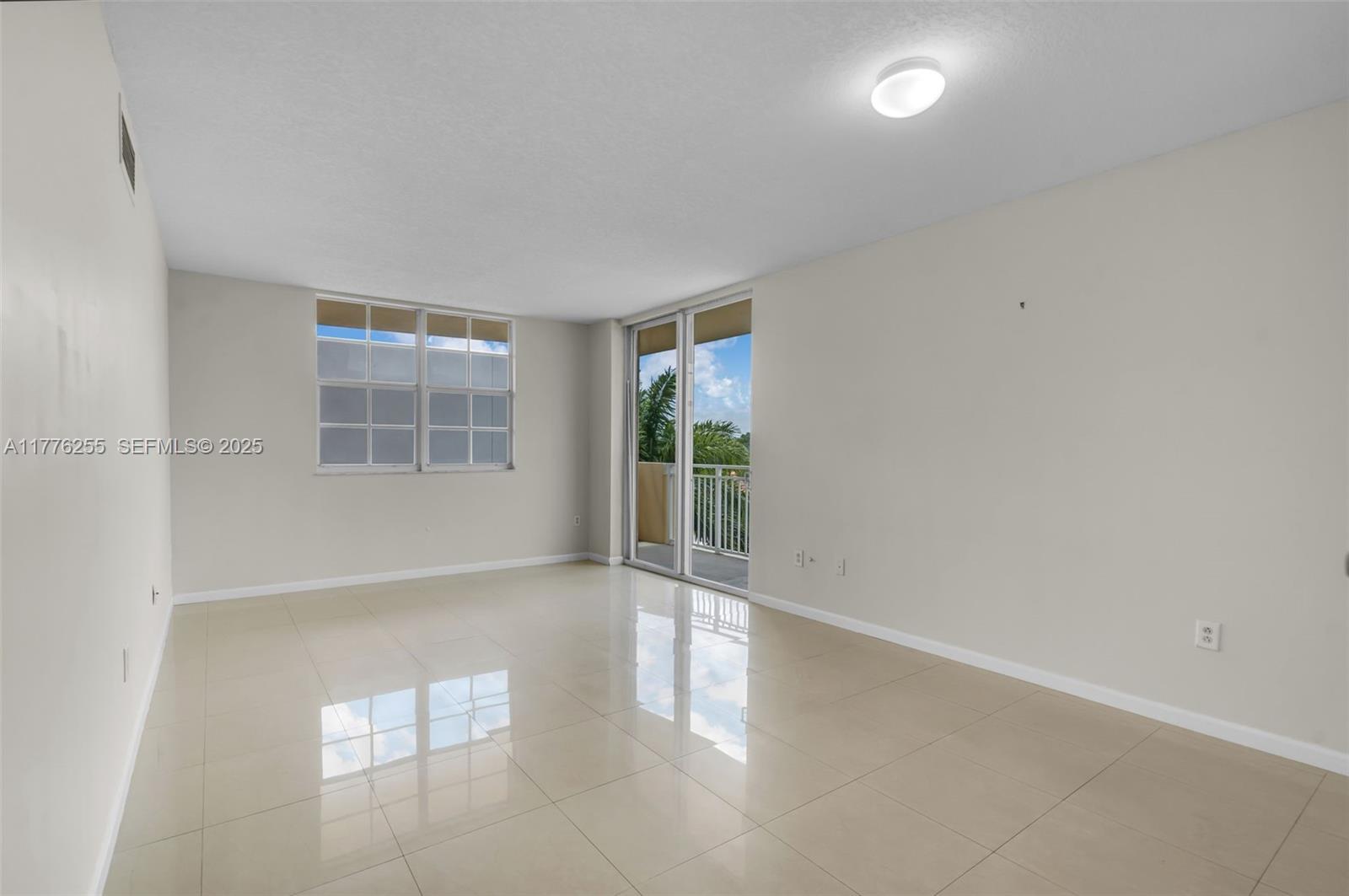 An empty room with beige tile floors, light-colored walls, a window, and a sliding glass door — 215 SW 42nd Ave # 402, Miami FL 33134, MIAMI, FL