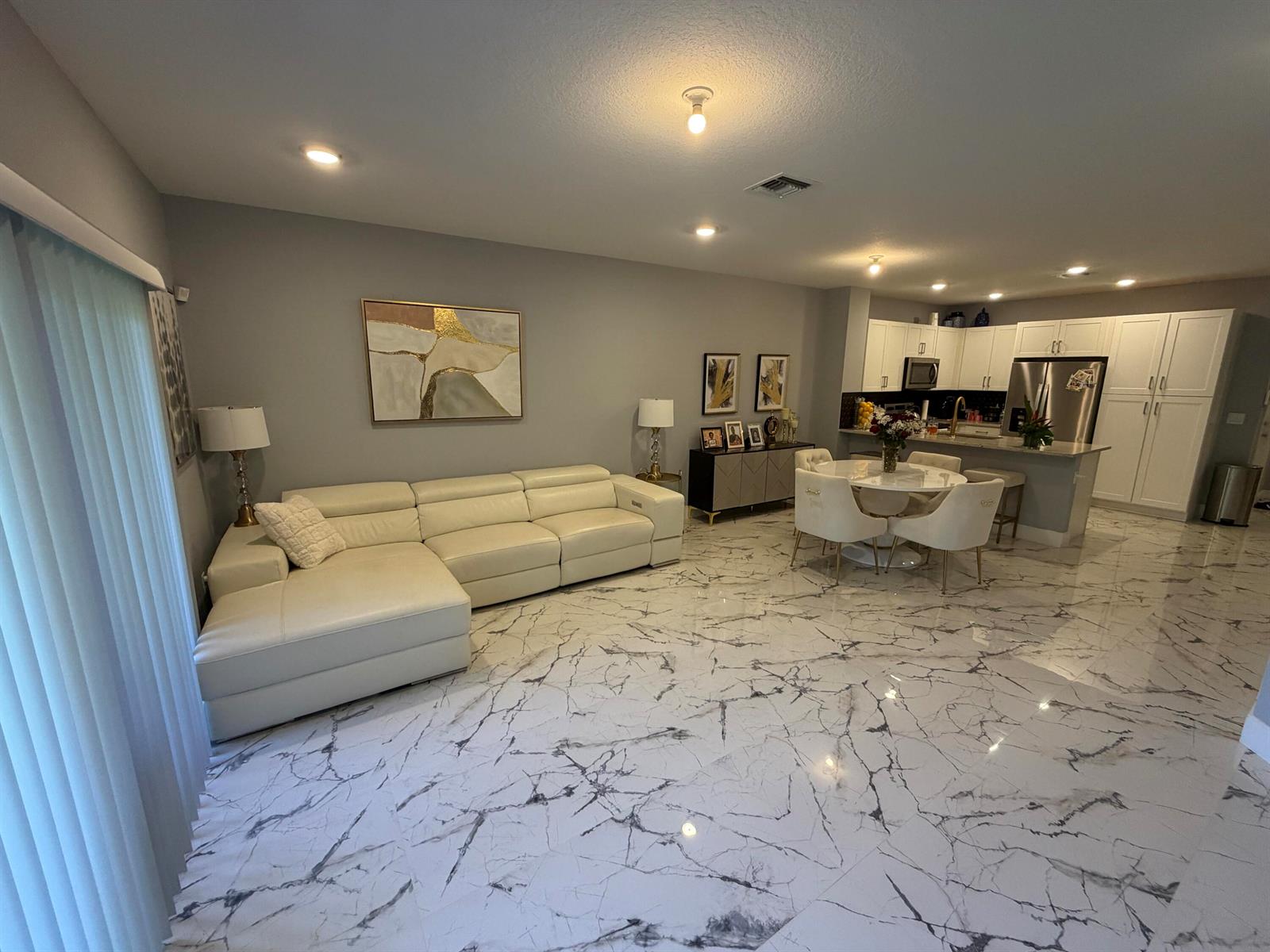 An open-concept living and dining area features white leather furniture and marble-patterned tile flooring — 178 SE 5th Court SE, Deerfield Beach FL 33441, DEERFIELD BEACH, FL