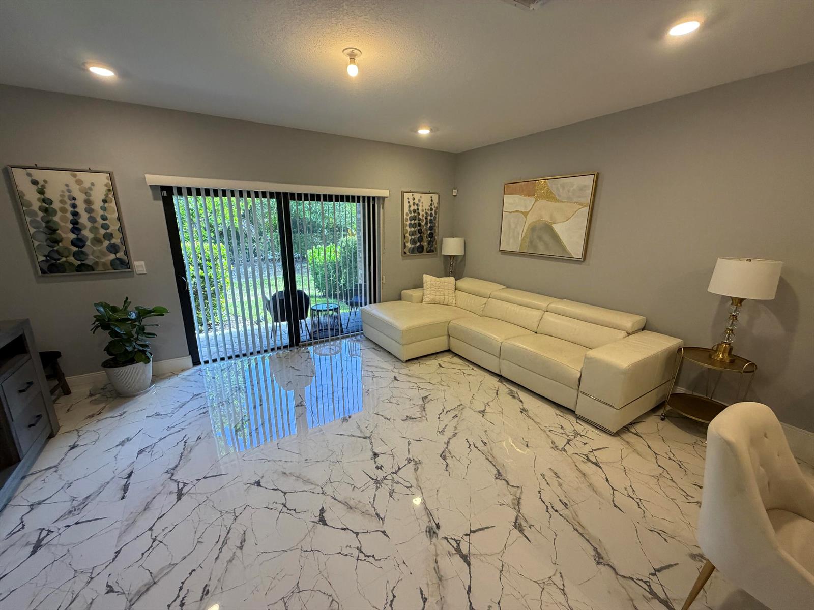 A living room features a white sectional sofa, marble-look tile flooring, and sliding glass doors — 178 SE 5th Court SE, Deerfield Beach FL 33441, DEERFIELD BEACH, FL