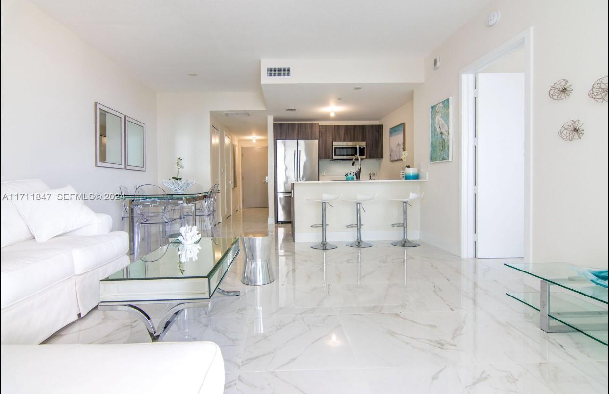 A bright, open-concept living and dining area features white marble floors and a modern kitchen — 488 NE 18th St # 2705, Miami FL 33132, MIAMI, FL
