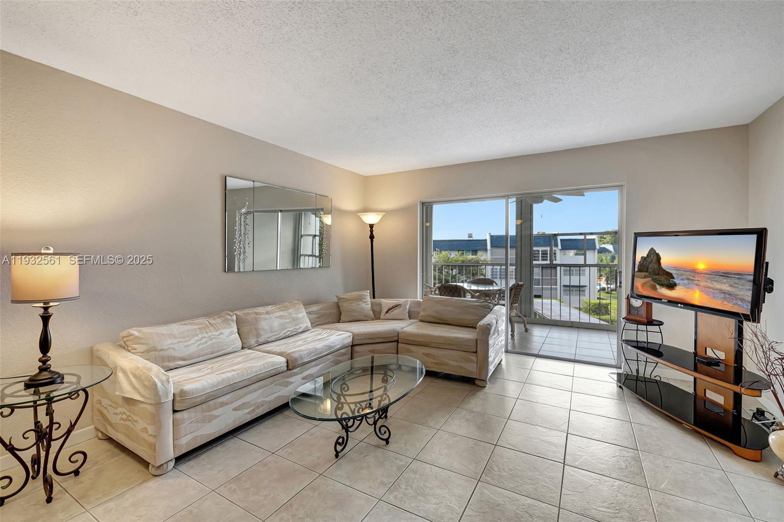 A living room features a beige sectional sofa, glass coffee table, and sliding glass balcony doors — 7897 Golf Circle Dr # 309, Margate FL 33063, MARGATE, FL
