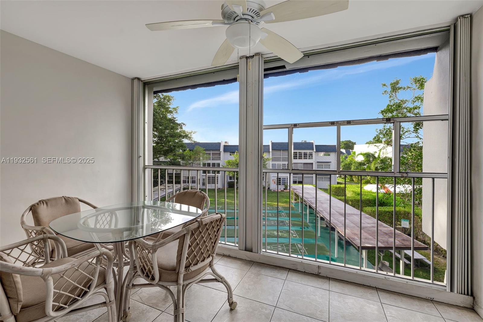 A screened-in balcony features a glass-topped table, wicker chairs, tile flooring, and a ceiling fan — 7897 Golf Circle Dr # 309, Margate FL 33063, MARGATE, FL