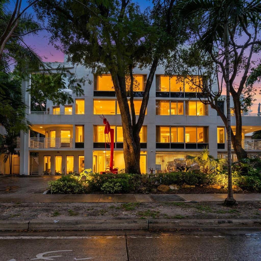 A multi-story white apartment building at dusk features large windows and a prominent red sculpture — 2100 Brickell Avenue # 404, Miami FL 33129, MIAMI, FL
