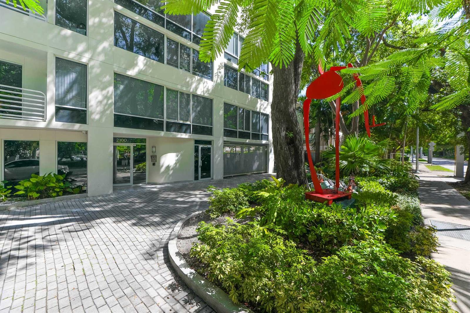The exterior of a multi-story apartment building features a paved driveway and a red sculpture — 2100 Brickell Avenue # 404, Miami FL 33129, MIAMI, FL