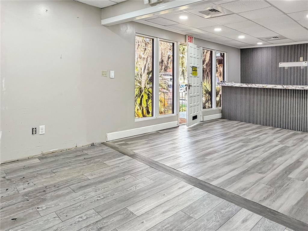 A room with gray wood-look flooring, a bar area, and an exterior door — 4131 UNIVERSITY BOULEVARD S UNIT 5, JACKSONVILLE, FL