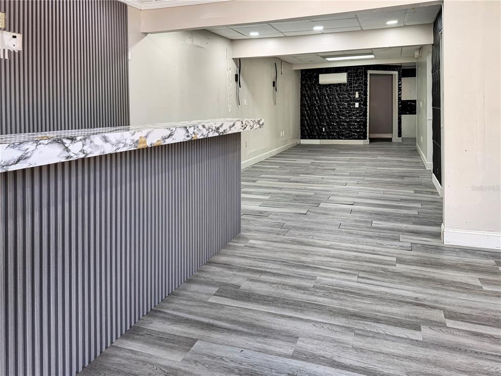 An interior view of a commercial space featuring a marble-topped counter and gray wood flooring — 4131 UNIVERSITY BOULEVARD S UNIT 5, JACKSONVILLE, FL
